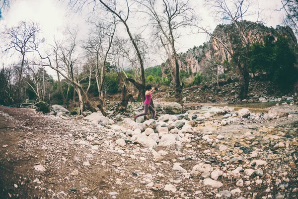 Mulher salta sobre o rio da montanha . — Fotografia de Stock