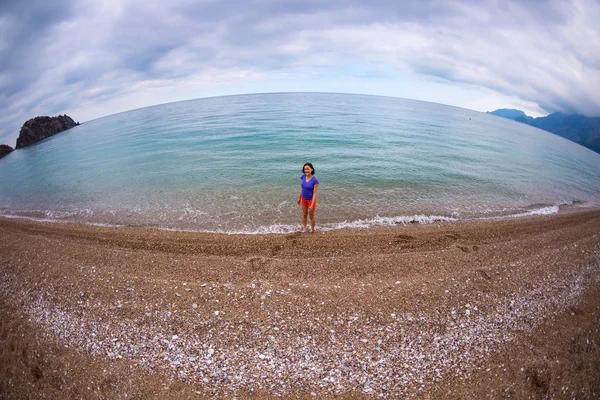 A woman walks alone on the sea coast.