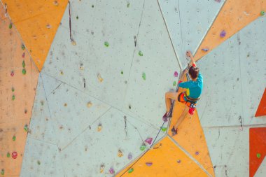 Bir kız bir tırmanma duvarı tırmanıyor.