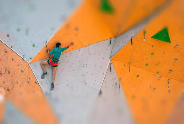 Una chica trepa por un muro de escalada . — Foto de Stock