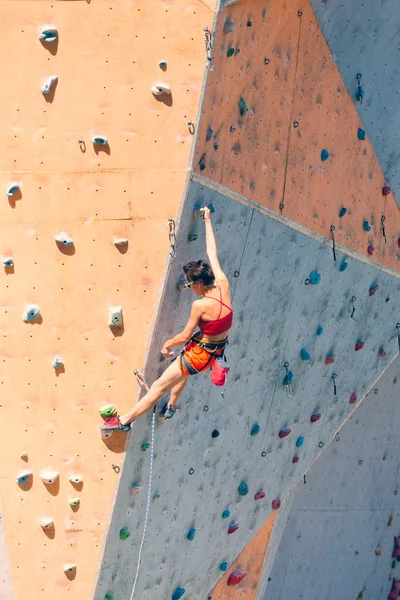 Uma menina sobe uma parede de escalada . — Fotografia de Stock