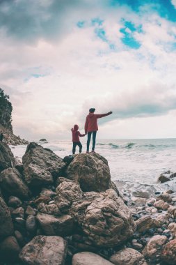 Bir kadın ve bir çocuk deniz ve gökyüzü karşı silüeti.