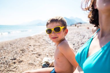 Annesi ile çocuk sahilde güneşlenmek.
