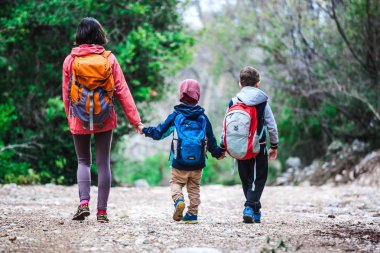 İki çocuklu bir kadınla orman geçer. 