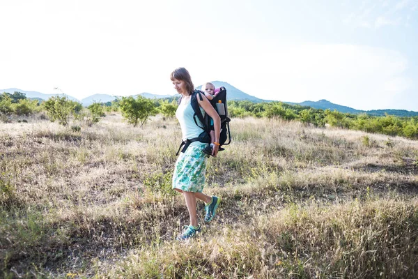 Una mujer lleva una mochila con su bebé. . —  Fotos de Stock