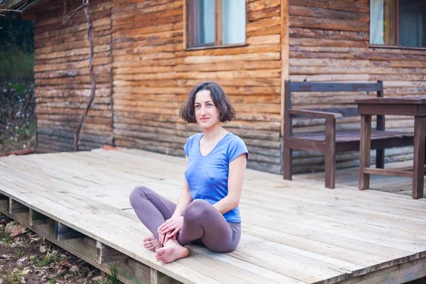 Eine Frau sitzt auf der Veranda eines alten Holzhauses. — Stockfoto