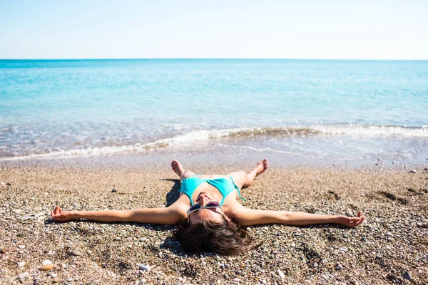 A menina toma banho de sol na praia . — Fotografia de Stock