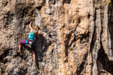 Bir kız bir kaya tırmanıyor.