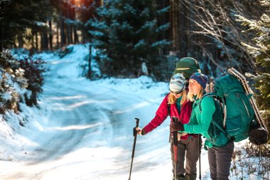 Bir kış yürüyüşünde iki gülümseyen kadın.