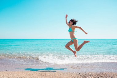 Kız sahilde atlama bir mayo içinde.