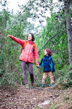 Orman yoluyla oğluyla bir kadın yürüyor. 