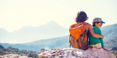 Çocuk ve annesi dağ üstüne oturuyor.