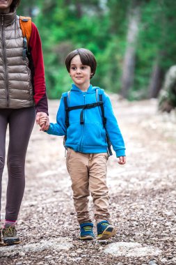 Orman yoluyla oğluyla bir kadın yürüyor. 