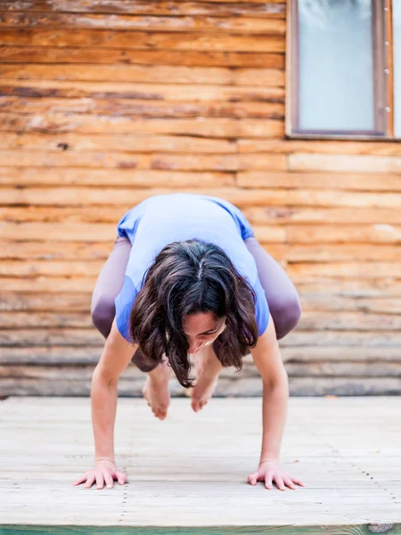 Una donna pratica yoga sotto il portico di una vecchia casa di legno . — Foto Stock