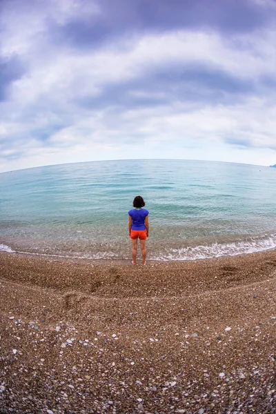 Una mujer camina sola en la costa del mar . — Foto de Stock