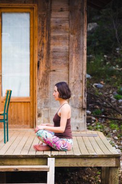 Bir kadın eski bir ahşap ev verandada yoga uygulamaları.