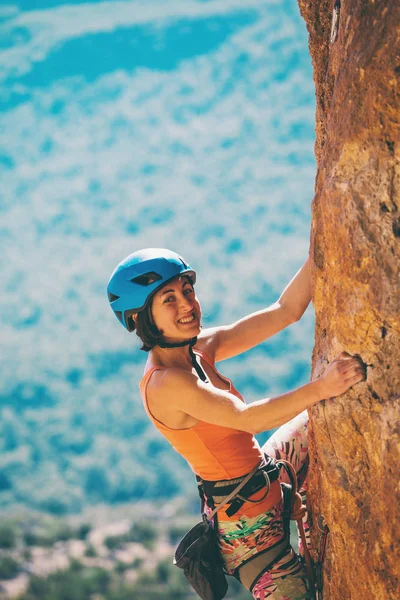 Una chica en un casco sube a una roca . — Foto de Stock