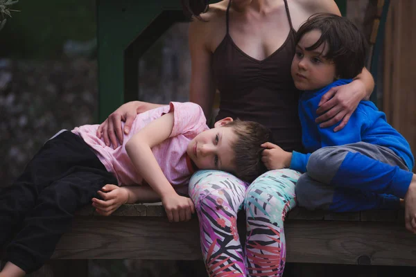 Mulher abraçando crianças no terraço de uma casa de madeira . — Fotografia de Stock