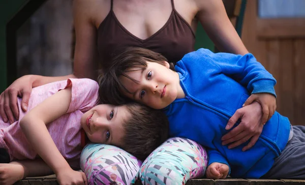 Mulher abraçando crianças no terraço de uma casa de madeira . — Fotografia de Stock