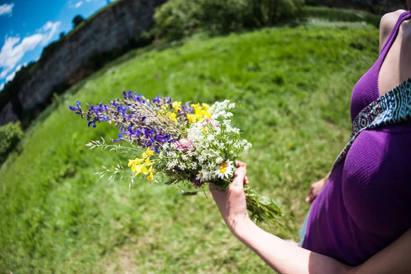 The girl is holding out a bouquet of wildflowers. — Stock Photo, Image