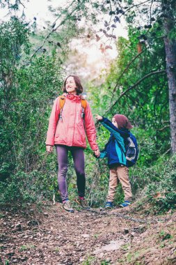Orman yoluyla oğluyla bir kadın yürüyor. 
