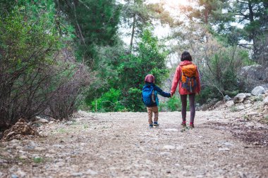 Orman yoluyla oğluyla bir kadın yürüyor. 