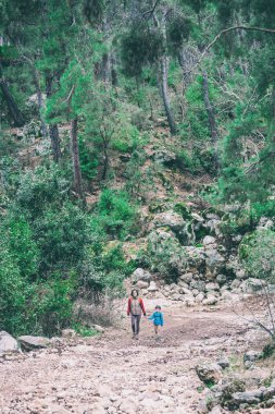 Çocuk annesi ile bir dağ yolda yürür..