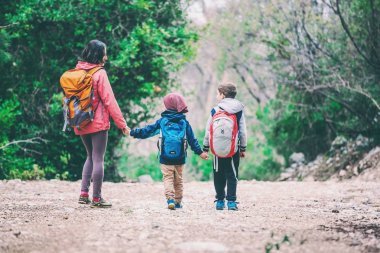 İki çocuklu bir kadınla orman geçer. 