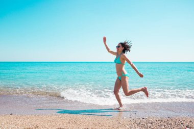 Kız sahilde atlama bir mayo içinde.