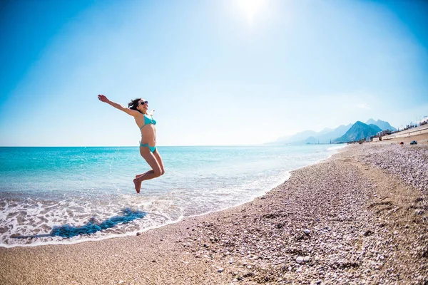 Κορίτσι σε ένα κοστούμι λουσίματος άλμα στην παραλία. — Φωτογραφία Αρχείου