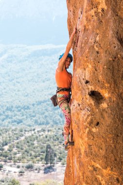 Bir kız bir kask içinde bir kaya tırmanıyor.