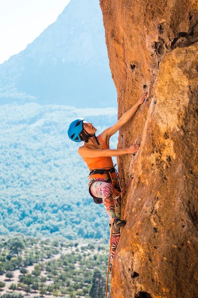 Una chica en un casco sube a una roca . — Foto de Stock