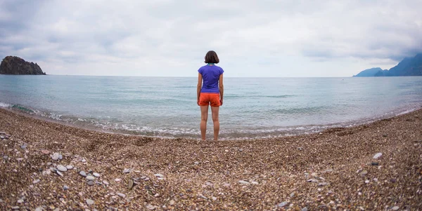 Una mujer camina sola en la costa del mar . — Foto de Stock