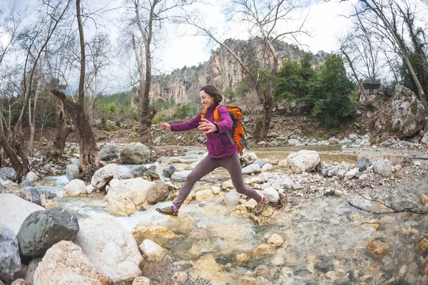 Mulher salta sobre o rio da montanha . — Fotografia de Stock