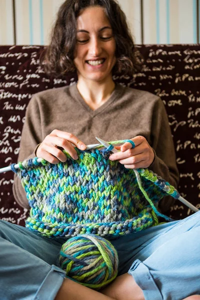 A woman knits from thick yarn.