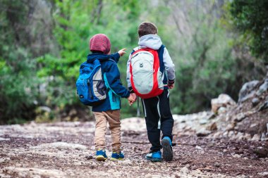 İki erkek sırt çantası ile bir orman yolu boyunca yürüyor.