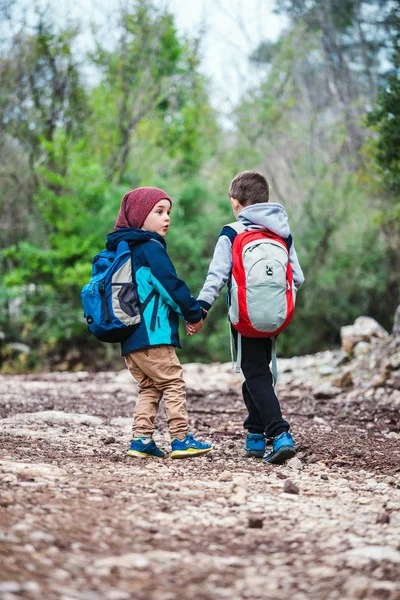 バックパックを持つ2人の少年は、森林のパスに沿って歩いています. — ストック写真