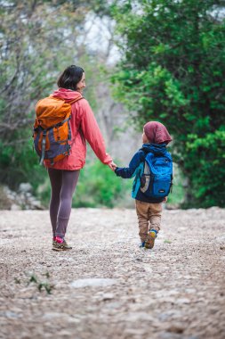 Orman yoluyla oğluyla bir kadın yürüyor. 