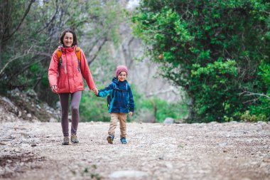 Orman yoluyla oğluyla bir kadın yürüyor. 
