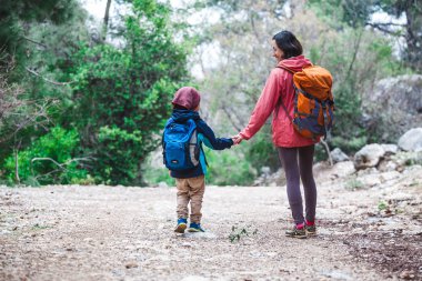 Orman yoluyla oğluyla bir kadın yürüyor. 