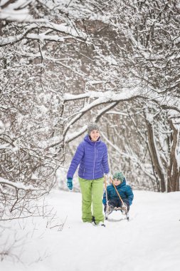 Bir kadın bir çocuğu kızak üzerine yuvarlar.. 