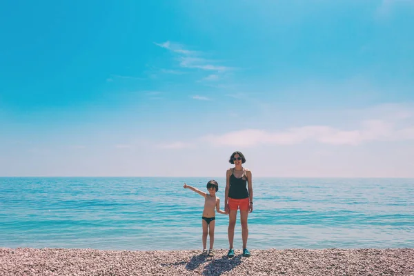 Chłopiec z matką stojącą na plaży i patrząc na morze. — Zdjęcie stockowe
