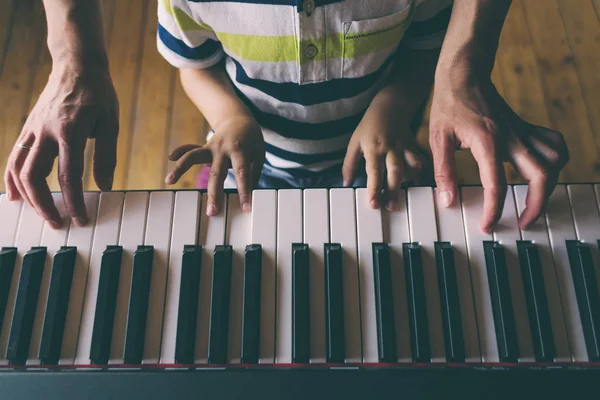 Tangan anak-anak dan perempuan pada kunci piano . Stok Gambar