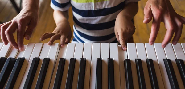Piyano anahtarlarında çocuk ve kadın elleri.