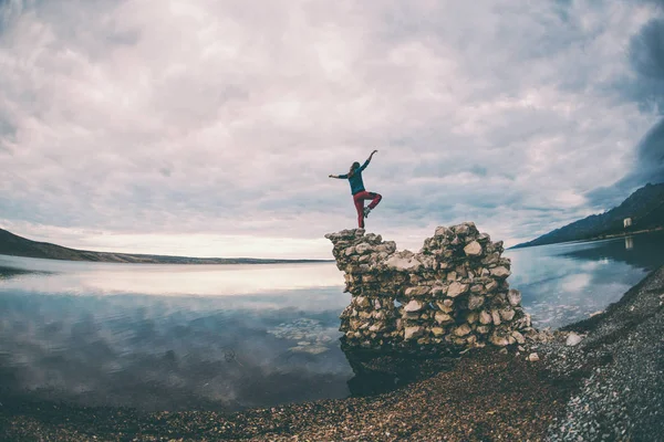 La chica se para sobre un montón de piedras y mira al mar . — Foto de Stock