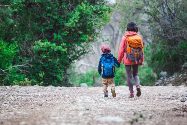 Orman yoluyla oğluyla bir kadın yürüyor. 