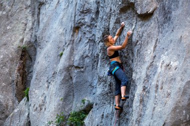 Bir kız bir kaya tırmanıyor.