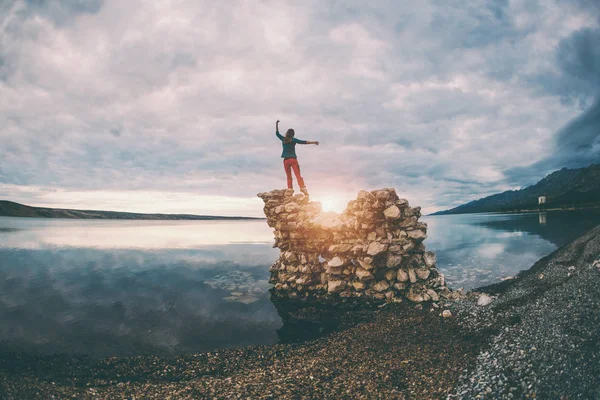 La chica se para sobre un montón de piedras y mira al mar . — Foto de Stock