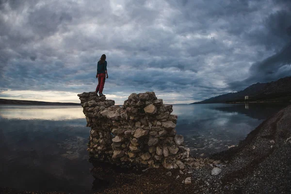 女孩站在一堆石头上,看着大海. — 图库照片
