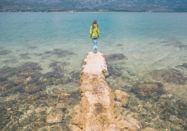 Een vrouw staat op een stenen Pier. — Stockfoto